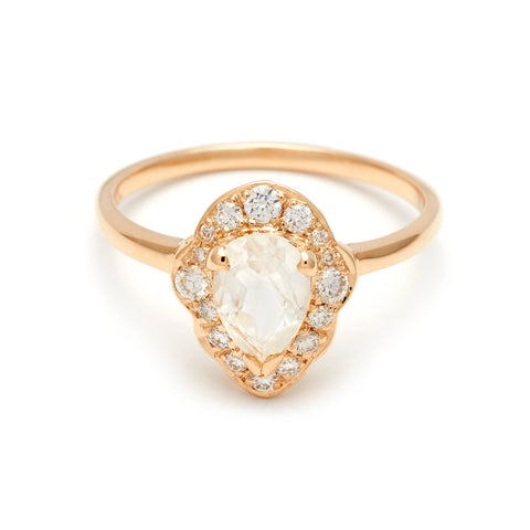 A pear shaped rainbow moonstone center ring set in a halo of white diamonds and in yellow gold.