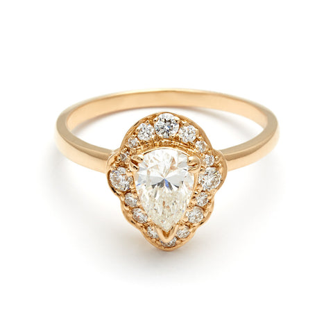 A pear shaped white diamond set in a halo of white diamonds and in yellow gold.