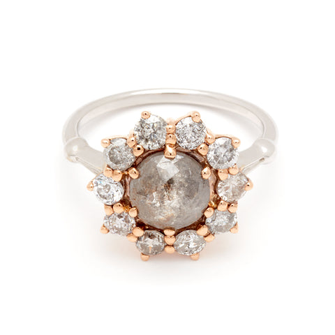 A ring with a rose cut grey diamond center stone surrounded by round grey diamonds set in a rose gold basket and white gold band.