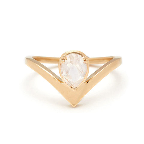 A pear shaped ring with a rainbow moonstone center stone set in yellow gold.