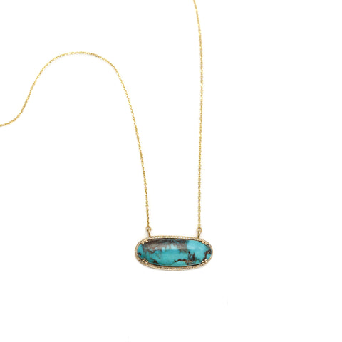 An amulet necklace with a turquoise center stone with a white diamond halo set in yellow gold.