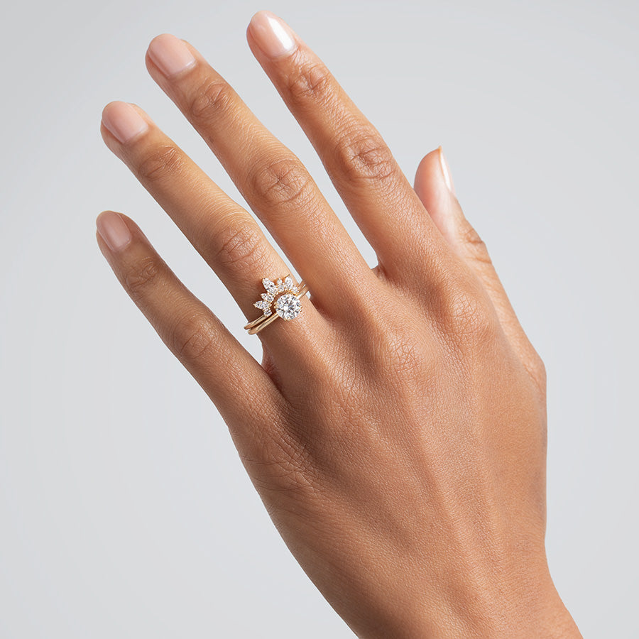 A band with three marquise shaped white diamonds with round white diamond set in yellow gold stacked above a solitaire round white diamond engagement ring on a medium-complexion hand., Yellow Gold, Rose Gold, White Gold
