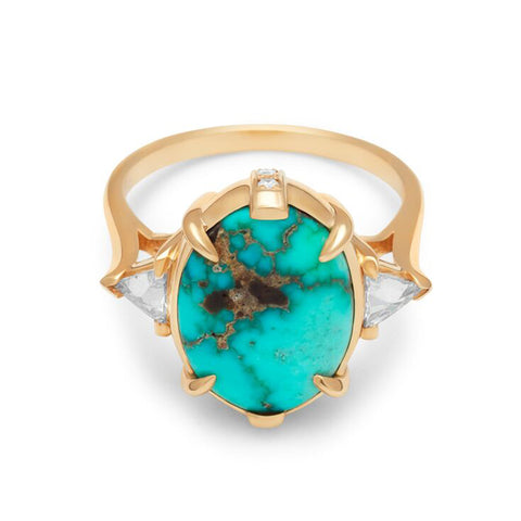 A three stone engagement ring with an oval shaped turquoise center stone with claw prongs two white diamond trillion side stones set in yellow gold.