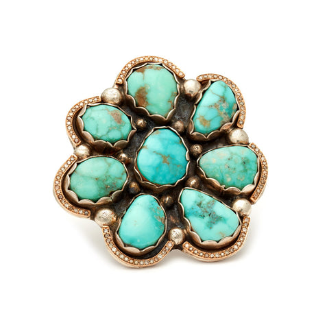 A flower shaped ring with turquoise stones and white diamond halo set in sterling silver and yellow gold.