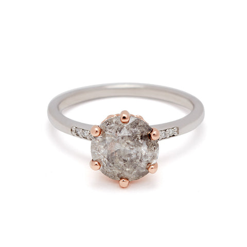 A solitaire ring with a round grey diamond with white diamond pave on either side set in a rose gold basket and a white gold band.