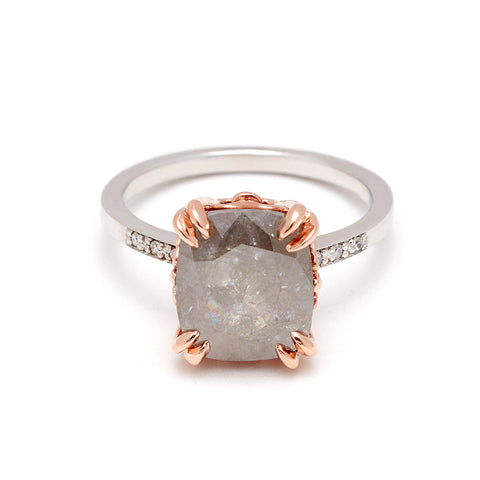 A solitaire ring with a cushion cut grey diamond with white diamond pave on either side set in white gold.