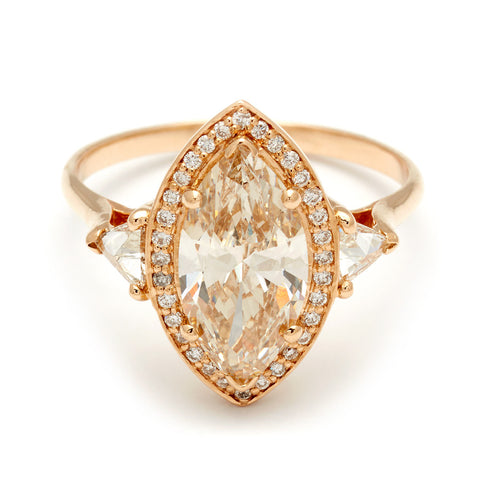 A three stone engagement ring with a marquise shape yellow diamond center stone surrounded by a lab white diamond with two lab white diamond trillion side stones set in yellow gold., Yellow Gold