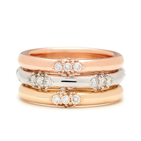 Three straight bands one with five clusters of white diamond accent stones stacked between two single cluster white diamond bands. 8