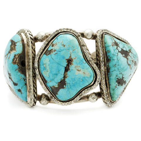 A three turquoise stones set in sterling silver with a halo of white diamond set in a cuff.
