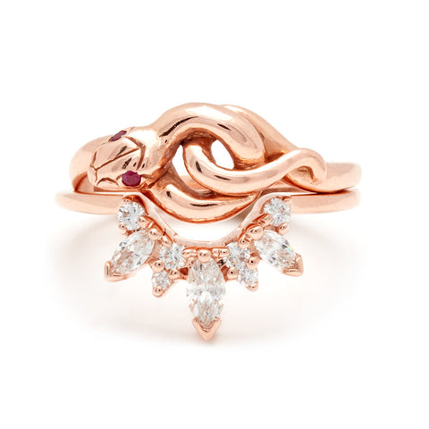 A serpent band with rubies for eyes set in rose gold stacked above a band with marquise and round white diamond stones in rose gold. 5
