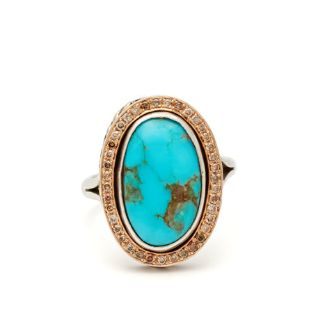 An engagement ring with an oval shape turquoise center stone surrounded by a champagne diamond pave halo set in yellow and white gold.