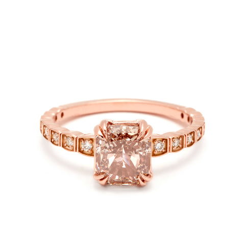 A solitaire ring with a cushion cut champagne diamond with white diamond pave around the band set in rose gold.