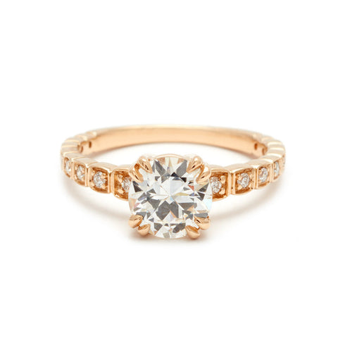 A solitaire ring with a euro cut white diamond with white diamond pave around the band set in yellow gold.